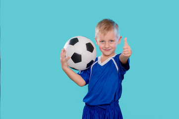 Happy little kid in sportswear holding a soccer ball isolated on blue background © Augustas Cetkauskas