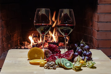 Two glasses of wine, cheese, bread and fruit on fire background