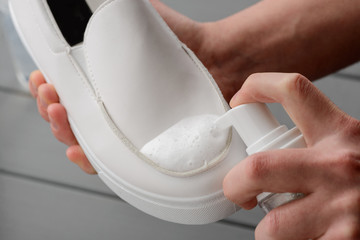 Man cleaning white leather shoes, close up on hands
