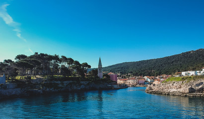 Fototapeta na wymiar Panoramic aerial photo of the village of Veli Losinj in the Croatian island. View towards the port or marina of the village. Beautiful colorful houses and church are seen.