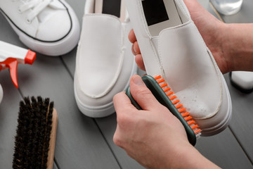 Man cleaning leather loafers, removing dirt with a brush and foam