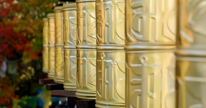 Bhuddhist prayer wheel golden inscribed with a sanskrit prayer and creamy bokeh .