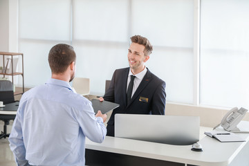 Male receptionist working with visitor in office
