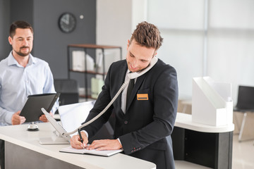 Male receptionist talking on phone in office