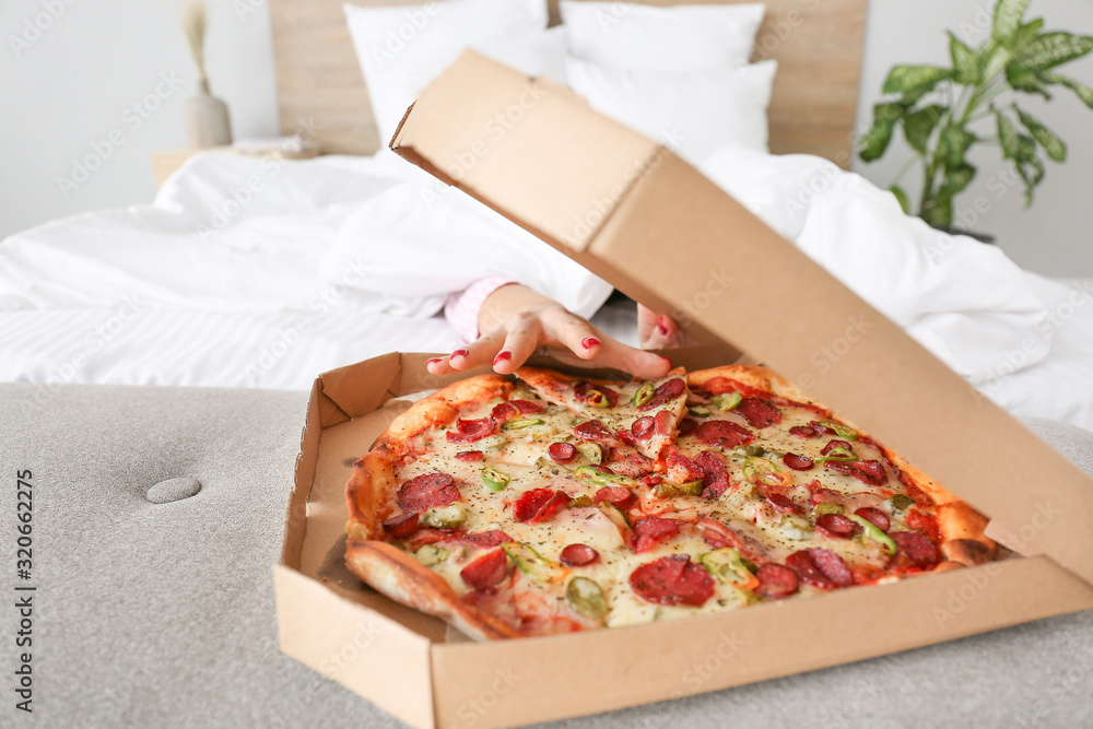 Wall mural morning of beautiful young woman eating tasty pizza in bedroom