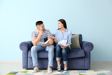 Young couple reading books while sitting on sofa at home