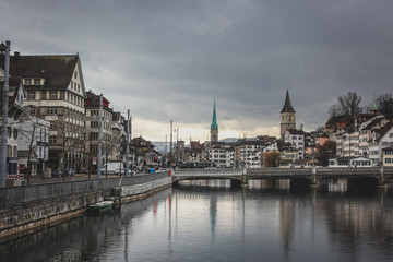 Fototapeta premium Cold and cloudy winter panorama of Zurich old town with Limmat river, bridges and St. Peter and Fraumunster church seen in the background.
