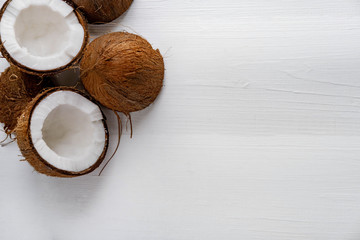 Half chopped coconut on a white wooden background. Tropical background with place for copy space. View from above