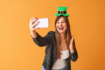 Funny young woman taking selfie on color background. St. Patrick's Day celebration