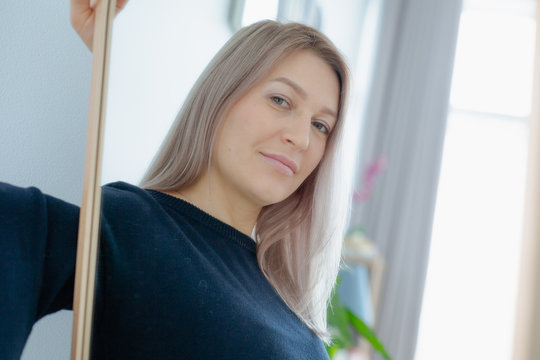blondie woman near the mirror in minimalistic apartment and posing