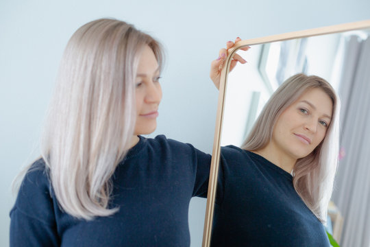 blondie woman near the mirror in minimalistic apartment and posing