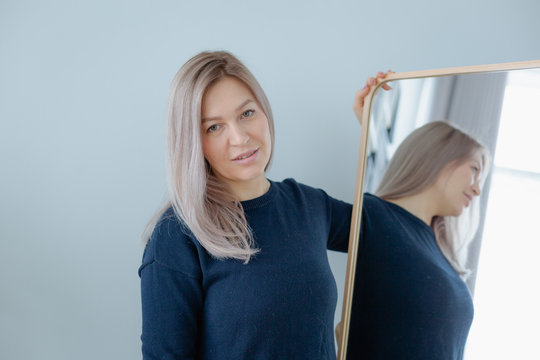 blondie woman near the mirror in minimalistic apartment and posing