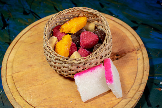 Wicker basket filled with typical Mexican sweets on a wooden board, alfajor, borrachitos, tamarind candy, cocada, dulce de leche