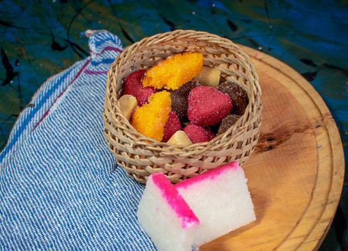 Wicker basket filled with typical Mexican sweets on a wooden board, alfajor, borrachitos, tamarind candy, cocada and dulce de leche