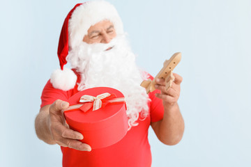 Santa Claus with toy airplane and gift on light background. Concept of vacation