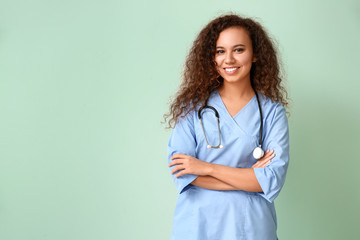 Young African-American nurse on color background - obrazy, fototapety, plakaty