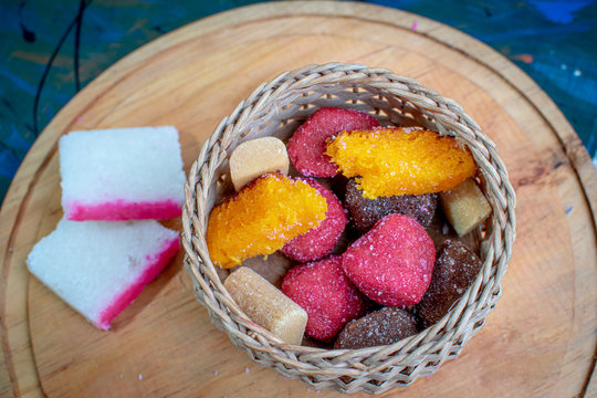 Wicker basket filled with typical Mexican sweets on a wooden board, borrachitos,alfajor, tamarind candy, cocada and dulce de leche