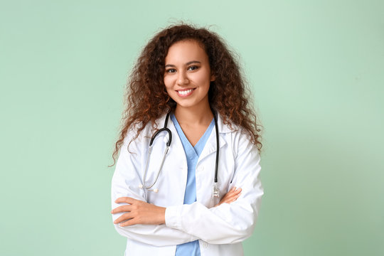 Young African-American doctor on color background