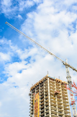 High-rise building under construction. The site with cranes against blue sky