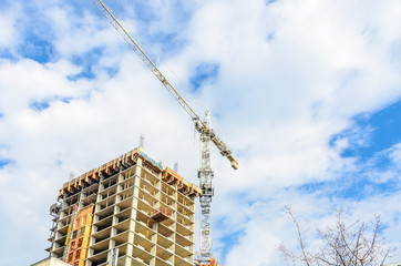 High-rise building under construction. The site with cranes against blue sky