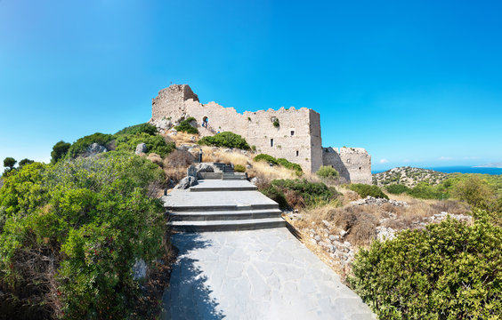 Stairs through bushes to ruins of medieval castle Kritinia with sea in backgraound (Rhodes, Greece)