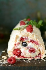 Meringue roll with a gentle airy cream, mint and fruit filling from raspberries, black currants, blueberries. Pavlova summer sweet dessert