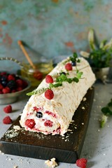 Meringue roll with a gentle airy cream, mint and fruit filling from raspberries, black currants, blueberries. Pavlova summer sweet dessert
