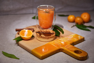 Exclusive painted art cutting board made of wood organic serving dishes with taste food cuisine orange juice hot drink spice cinnamon cake caramel sweet desert fresh leaves fruit citrus.