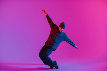 Fototapeta na wymiar Young Man in a Jumper Dancing Contemporary Dance in Studio. Breakdancing. Dance School Poster. Copy Space. Battle competition announcement. Pink and Blue Background.