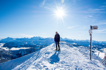 snow shoe hiker a the summit of the snowy mountain. panoramic picture of winter hiker at the top of the hill. gorgeous swiss alps mountain panorama with sun and blue sky