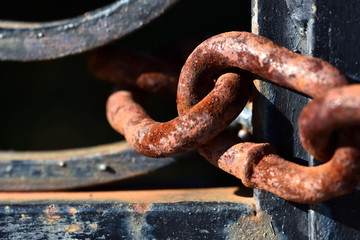 Textures of a rusty chain on an iron gate between lights and shadows