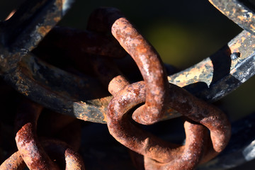 Textures of a rusty chain on an iron gate between lights and shadows