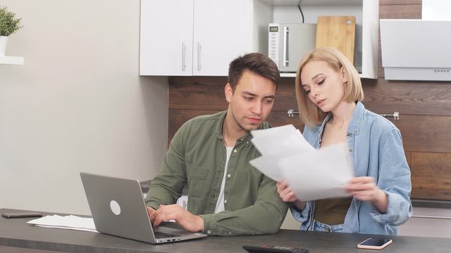 Married couple use laptop and documents, discuss mortgage, analyzing together, happy relationship between wife and husband