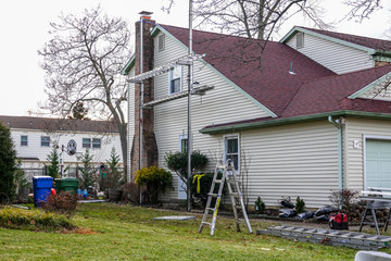 Scaffolding and ladder set up on the side of a home to allow residing of the house