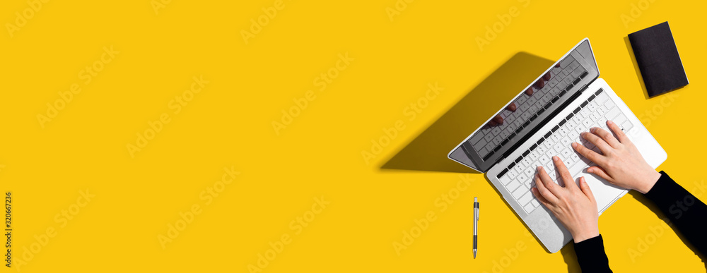 Poster person using a laptop computer on a solid color background