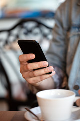 Close up of man hands holding smartphone. Watching him sms, messages, email in his cell phone cafe.