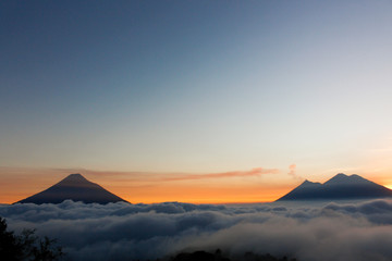 Fototapeta na wymiar Sunset over Volcano of Fire, Acatenango Volcano and Water Volcano - volcanoes surrounded by clouds - A view of the volcanoes of Guatemala