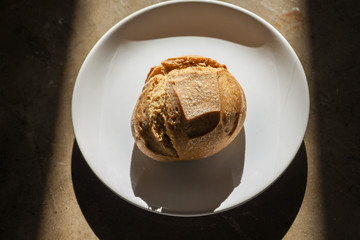 Soft fresh baked white bread with a crispy crust on a white plate on textured table