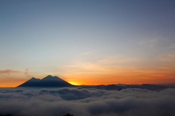 Fototapeta na wymiar Sunset over Volcano of Fire and Acatenango Volcano - volcanoes surrounded by clouds - A view of the volcanoes of Guatemala