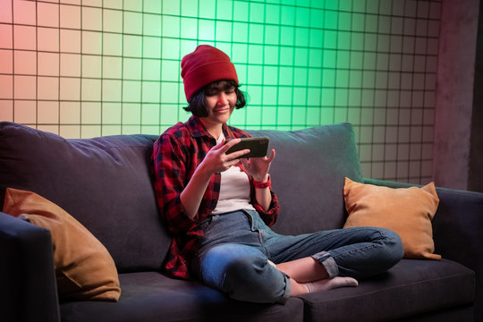 Teenager girl holding a smartphone while playing online shooting gaming.
