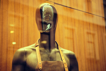 Stylish black mannequin in an apron on a store window.