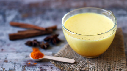 Turmeric milk with spices in a mug. Golden turmeric milk. Indian health drink. Selective focus. Macro.