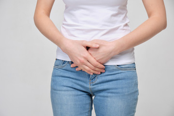 A girl in a white T-shirt massages the lower abdomen. close up.