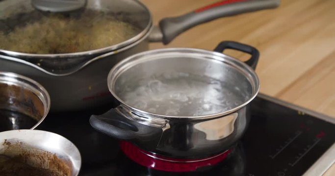 Pan full of boiling water with steam inside kitchen. Cooking concept.