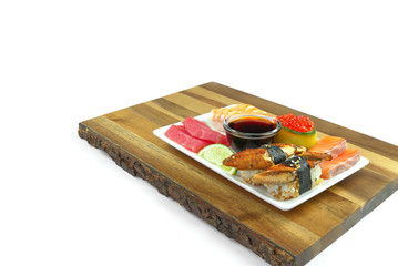 Fototapeta na wymiar traditional japanese sushi set on a white plate serviced on wood board. tasty set of sushi, nigiri, sahimi and maki. delicious dinner or lunch for one person. isolated on white