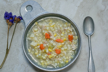 Chicken Corn soup with rivels in metal soup bowl.  It is an Amish classic soup recipe and includes chicken, corn, onion, carrots, celery and homemade dough rivels.