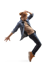 Young guy in jeans and woolen hat dancing on tiptoes