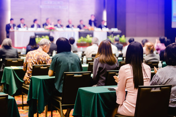 Selective focus to business woman sitting with blurry chairman of the meeting and executive committee background in auditorium for shareholders meeting or seminar event, Annual shareholder meeting. - obrazy, fototapety, plakaty