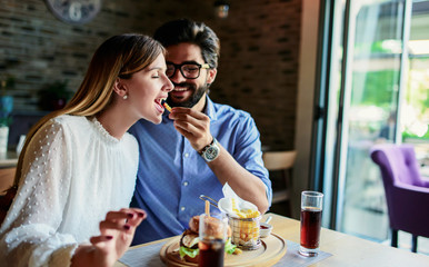 Young couple sitting in a cafe, having breakfast. Love, dating, food, lifestyle concept