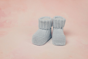 Little baby booties on soft pink background.